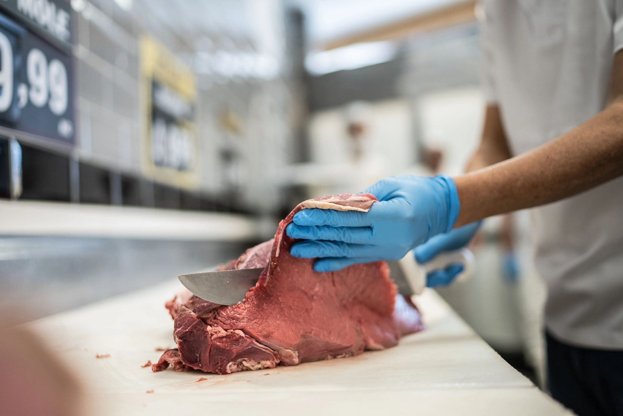 Butcher hands cutting fresh meat on a wooden board